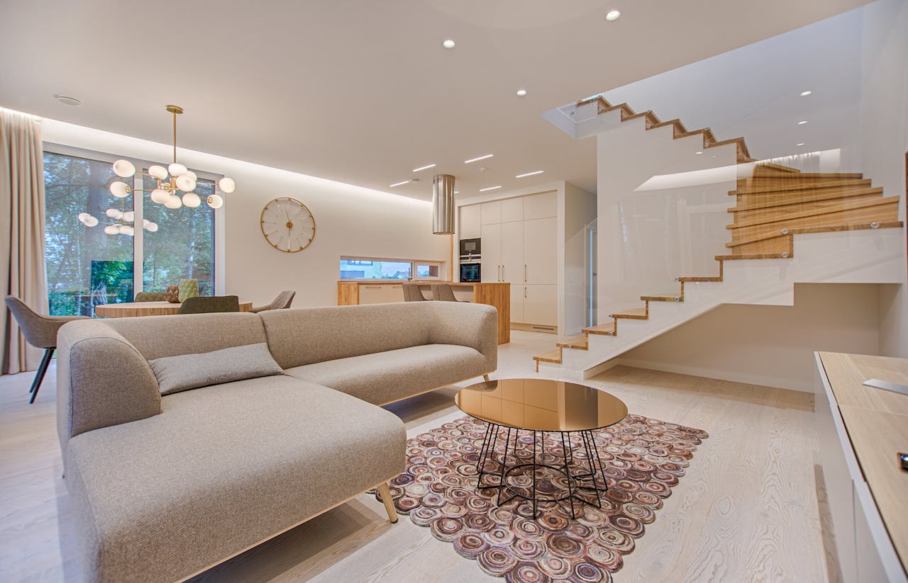 Home Contemporary living room with neutral tones, a sleek sofa, and elegant wooden staircase.